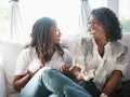 A mother & daughter laughing on the couch before posting pic on Instagram with mother-daughter frien...