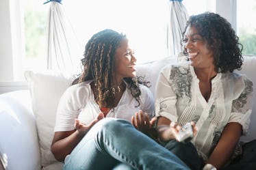 A mother & daughter laughing on the couch before posting pic on Instagram with mother-daughter frien...