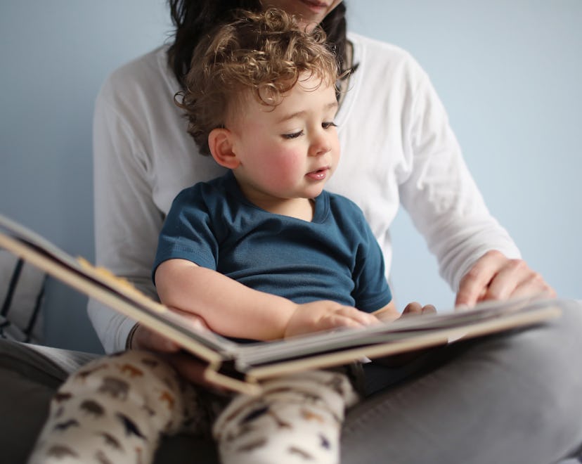 toddler sitting on mom's lap, reading a children's book