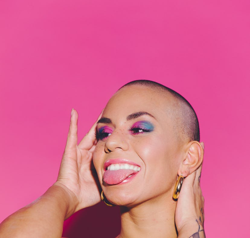 Young happy beautiful woman against a pink background sticking out her tongue on her 25th birthday, ...