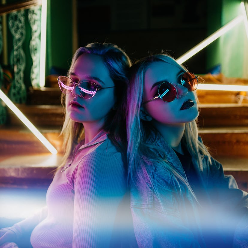 2 young woman posing back to back with sunglasses on during the full blue moon in Aquarius.