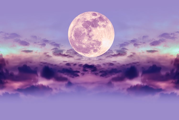 Purple nature background of night sky and silhouette of clouds with the August 2021 full blue moon i...