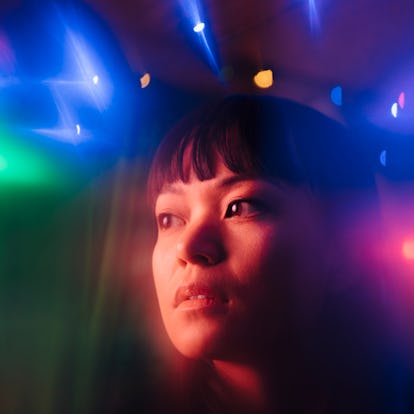 Young woman looking away amidst multi colored lights during the next blue moon.