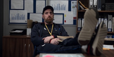 Coach Beard (Brendan Hunt) whose zodiac sign is Gemini, propping his feet up on his desk in the Appl...