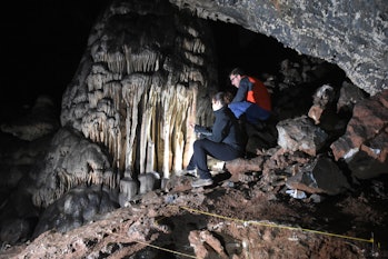 Researchers looking toward the massive speleothem of Cueva Ardales, with archaeological trench in th...