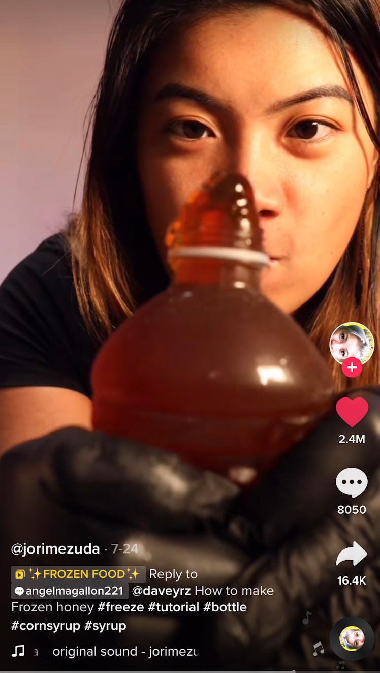 A woman pushes honey frozen corn syrup out of a bottle for TikTok. 