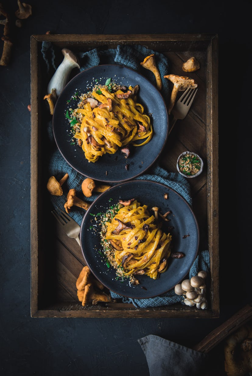 overhead shot of two dark blue bowls of squash and hazelnut fettuccine with sauteed mushrooms