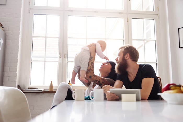 couple with tattoos, holding baby up in the air