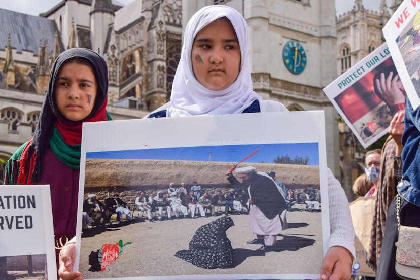A young girl holds a picture of a woman being publicly beaten, during the demonstration in Parliamen...