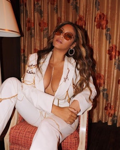 Beyoncé in white suit, posing on a chair.