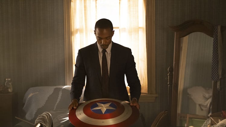 Sam Wilson (Anthony Mackie) wearing a suit and looking at captain americas new shield as he becomes ...