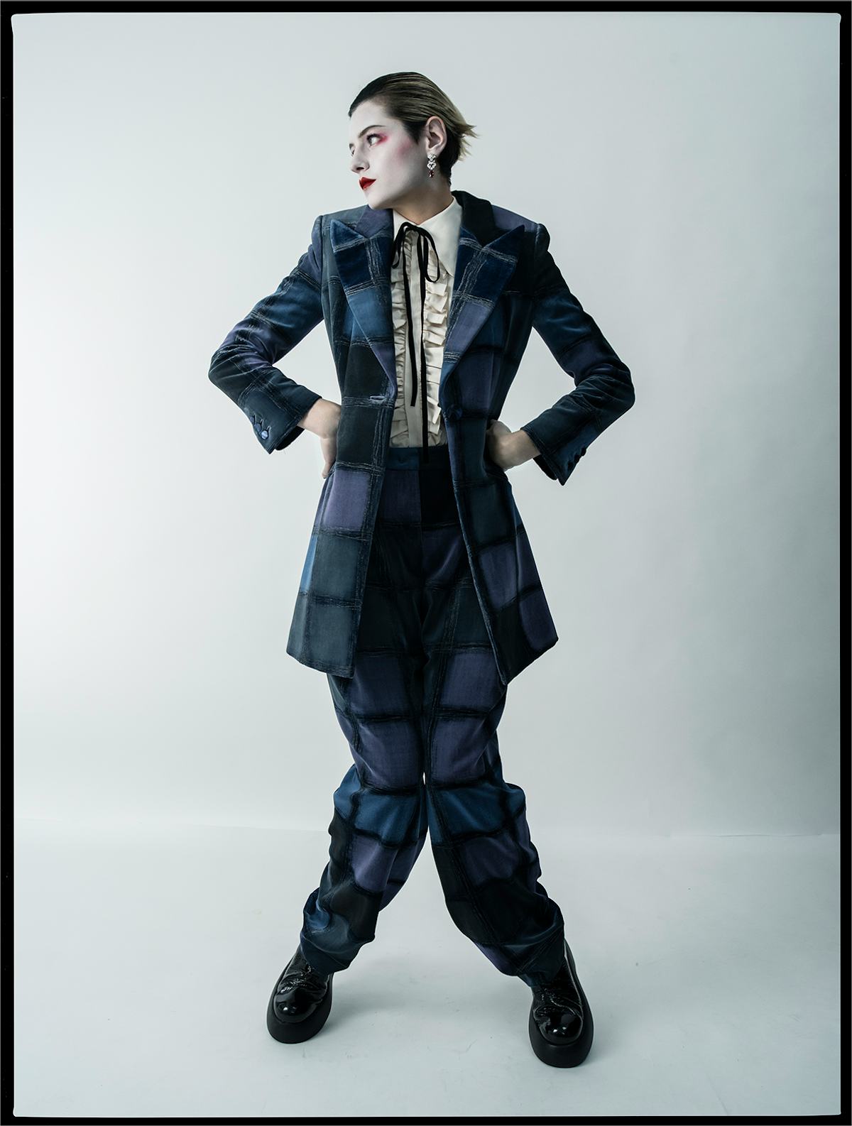 Emma Corrin wears a Giorgio Armani jacket and pants; Molly Goddard shirt; Cartier earrings; AGL shoe...