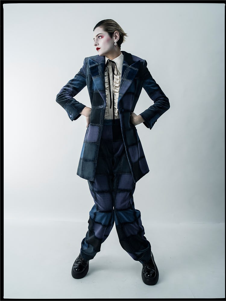 Emma Corrin wears a Giorgio Armani jacket and pants; Molly Goddard shirt; Cartier earrings; AGL shoe...