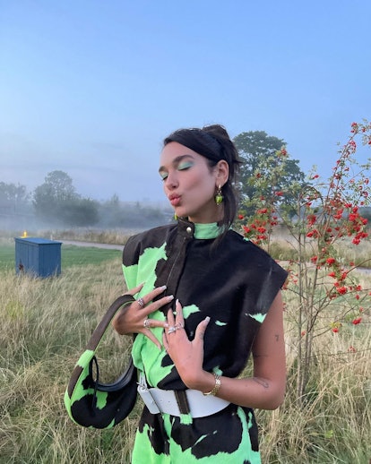 Dua Lipa posing in green cow print dress and green eyeshadow