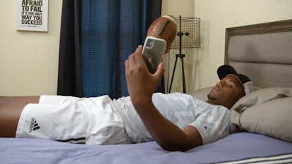 Amari Jones playing with a football in bed while on the phone on 'Titletown High'.