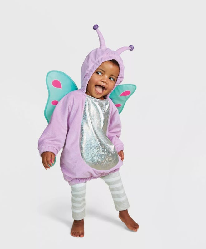 Baby/toddler girl standing, making a funny face, dressed in butterfly costume