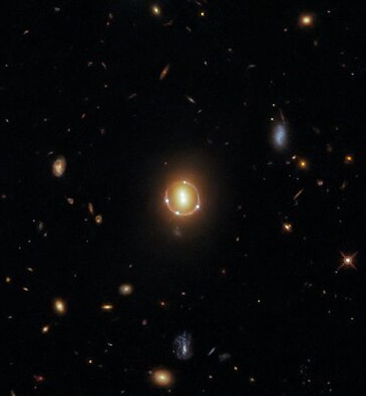 A Hubble image of the cluster, characterized by two bright spots in the center and four small light ...