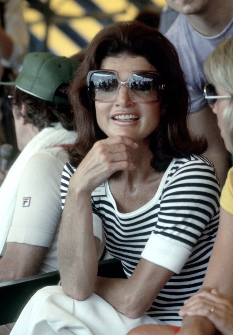 Jackie O at a sports tournament in a black and white striped shirt, white  pants and oversized sungl...