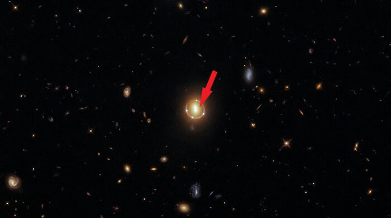 A Hubble image of the cluster with a red arrow pointing at the exact location