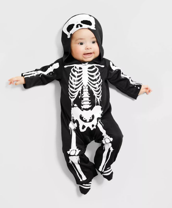 Baby laying down flat, wearing onesie with skeleton bones