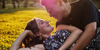 man and woman on the grass cuddling