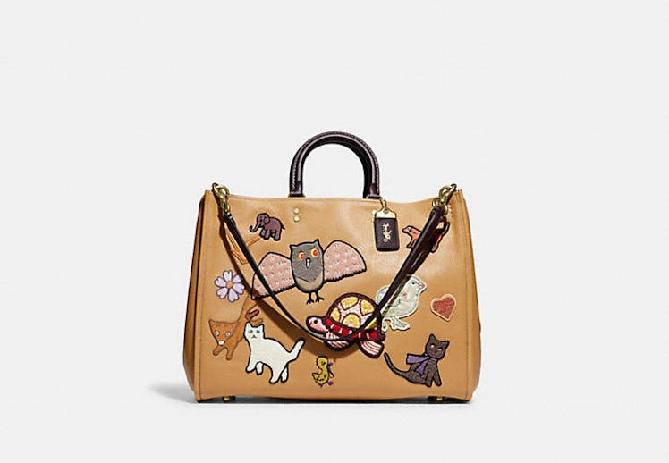 Coach Rogue 39 bag in tan leather with creature patches.