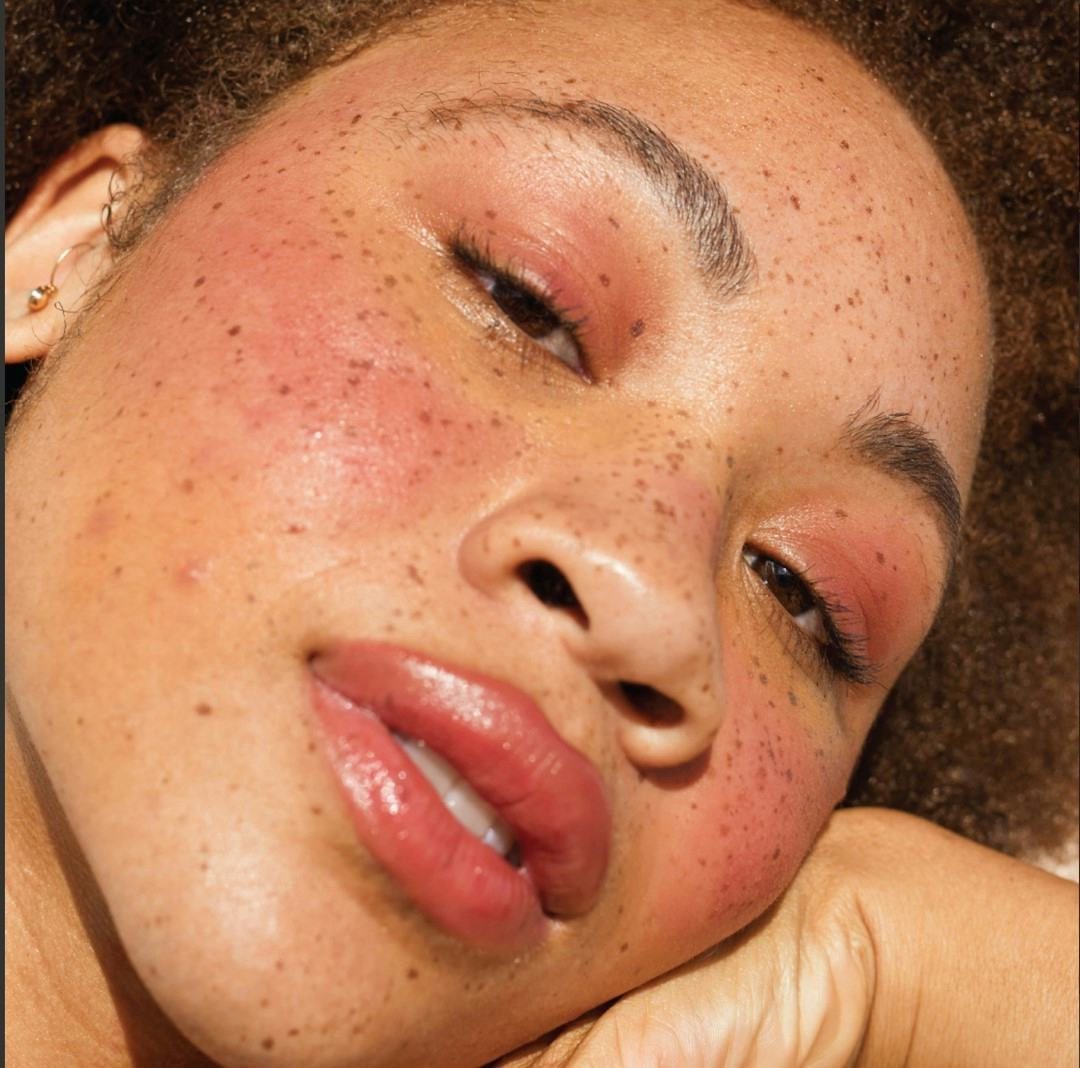 A woman with natural freckles wearing a coral lipstick for fall