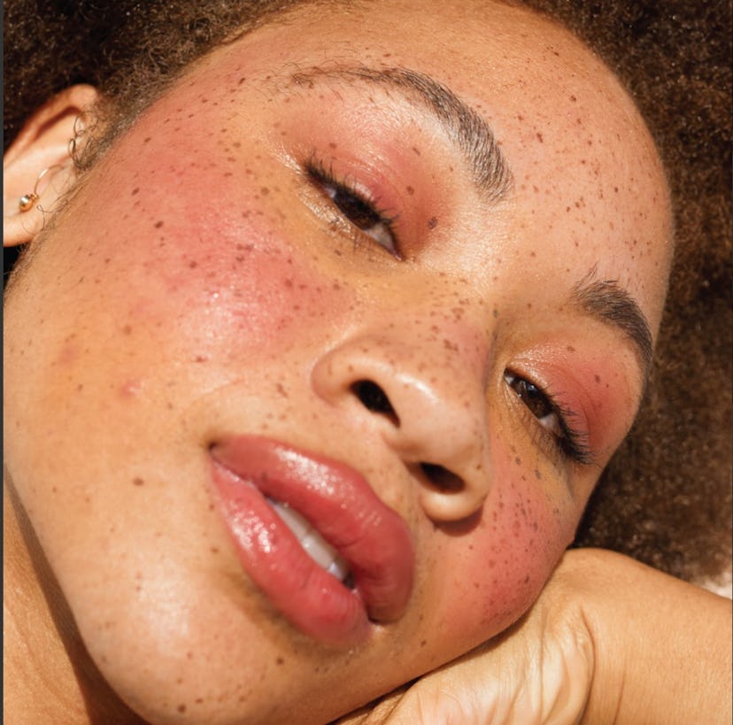 A woman with natural freckles wearing a coral lipstick for fall