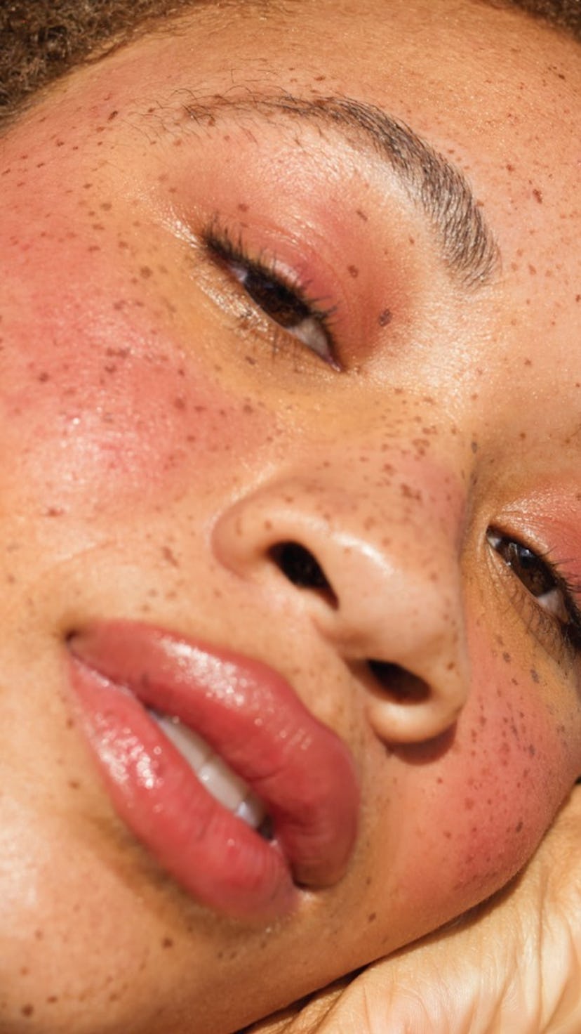 A woman with natural freckles wearing a coral lipstick for fall