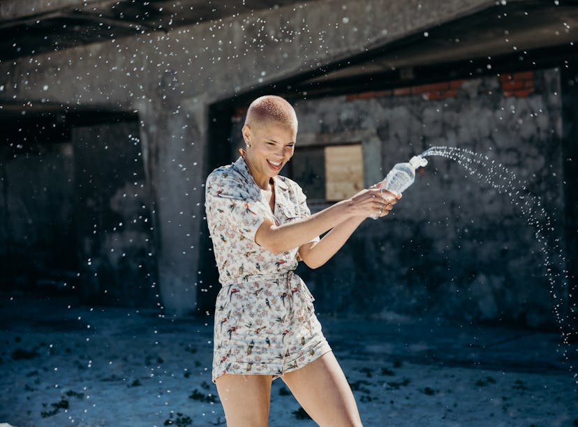 Young woman spraying water from a bottle, having the best week of September 6, 2021, per her zodiac ...