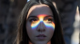 Young Woman Looking Away with rainbow light refracting off her face during the September 2021 new mo...