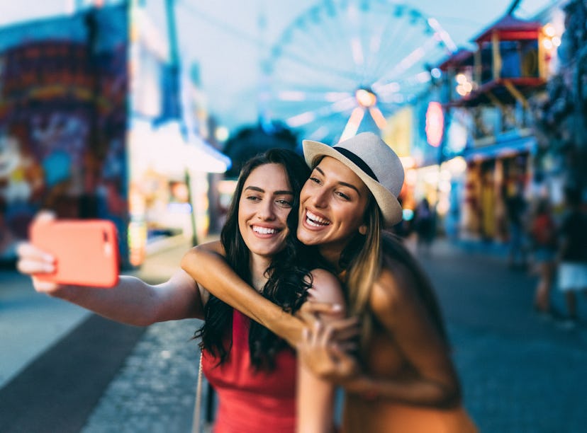 Friends taking a selfie at a fall fair before posting a photo on Instagram with a cute carnival capt...