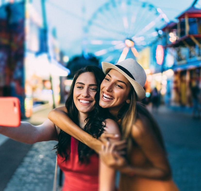 Friends taking a selfie at a fall fair before posting a photo on Instagram with a cute carnival capt...