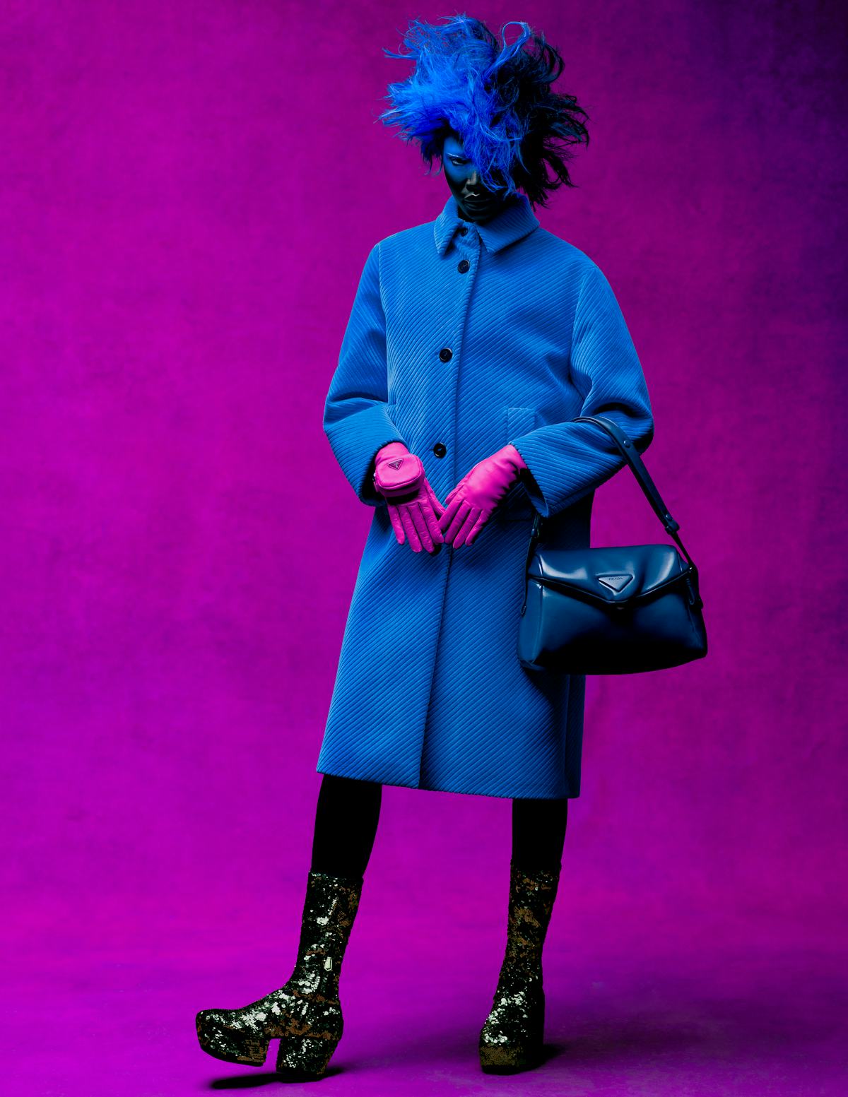 Adhel Bol wears a Prada coat, gloves, bag, and boots.