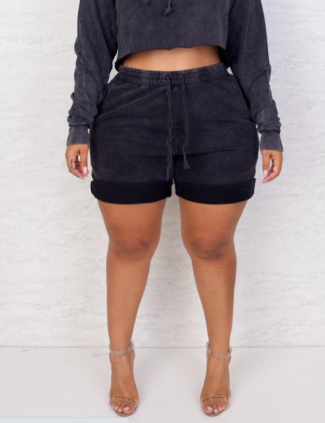 Model wearing black crop sweatshirt and black shorts with drawstring waist