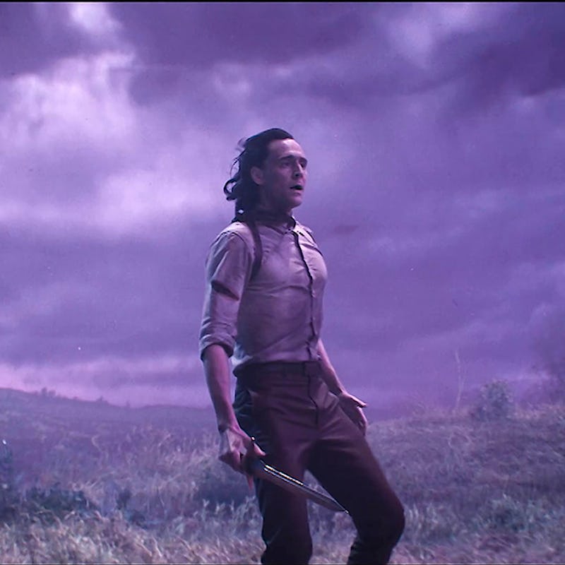 Loki standing on a hill with gloomy clouds above and wind blowing his hair to the back