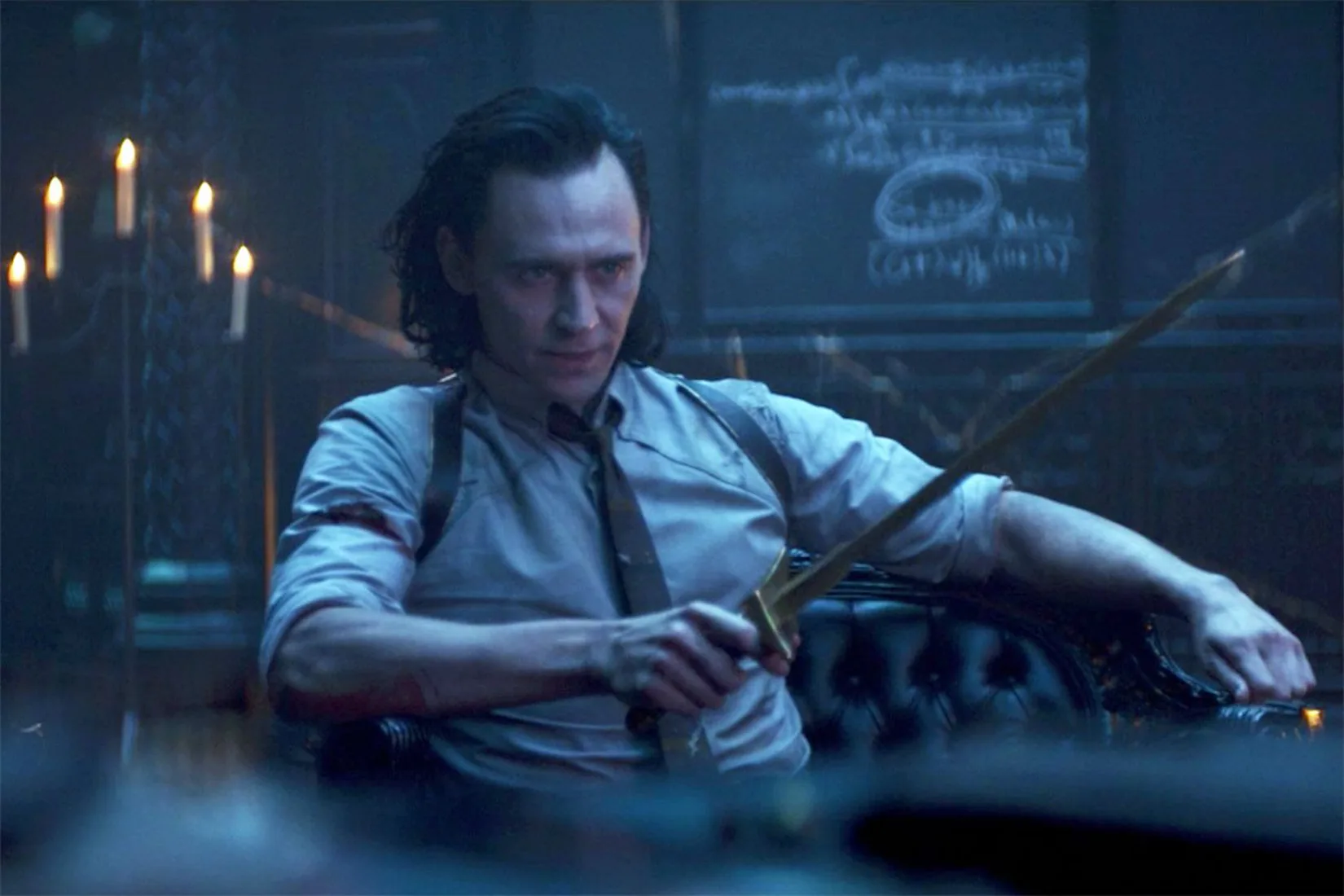 Loki sitting down and holding a sword pointing it forward