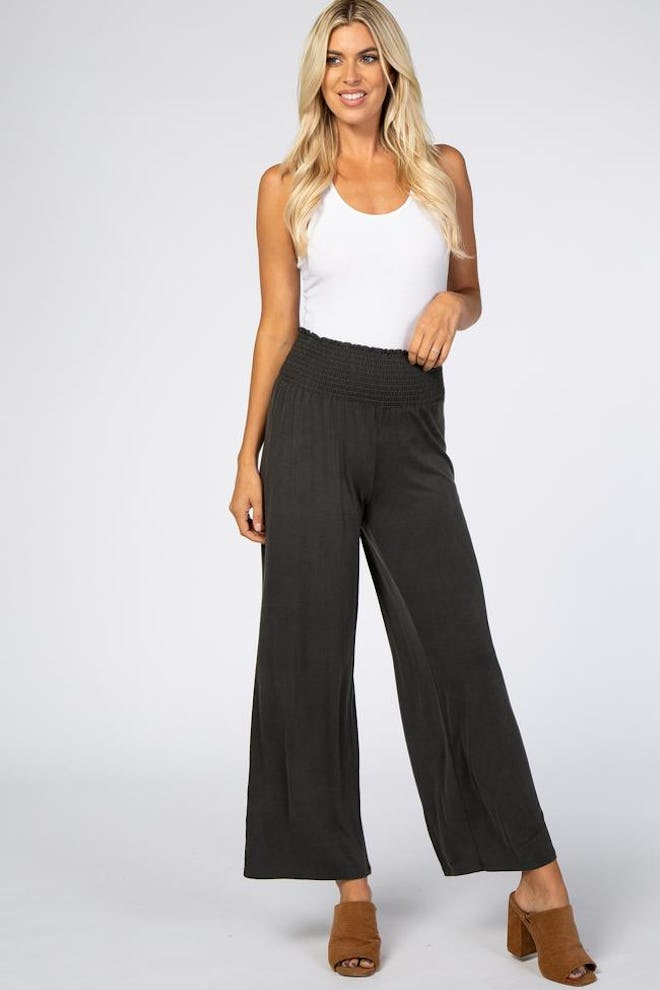 Woman standing; modeling black smock waisted flowy pants