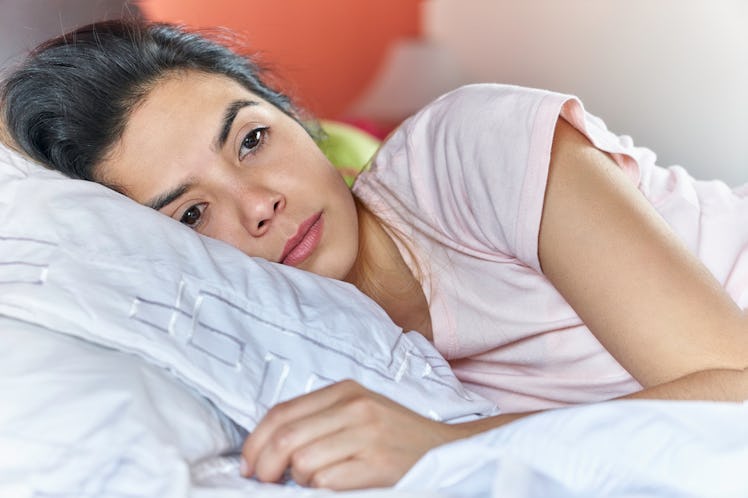Young woman not getting enough sleep due to her worsening period.