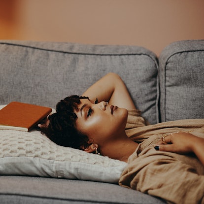 Young woman laying on the couch wondering does February mess up your period.