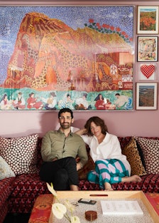 David Kordansky and Mindy Shapero seated on a red couch surrounded by artwork