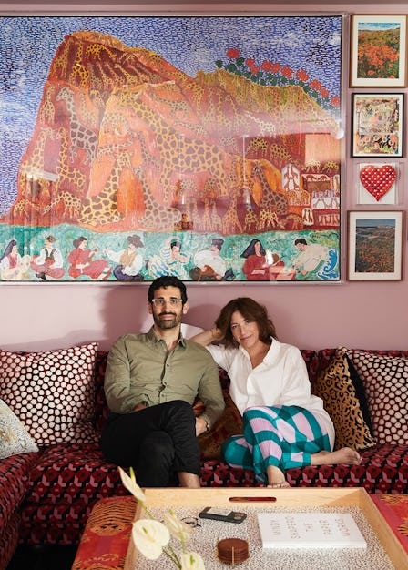 David Kordansky and Mindy Shapero seated on a red couch surrounded by artwork