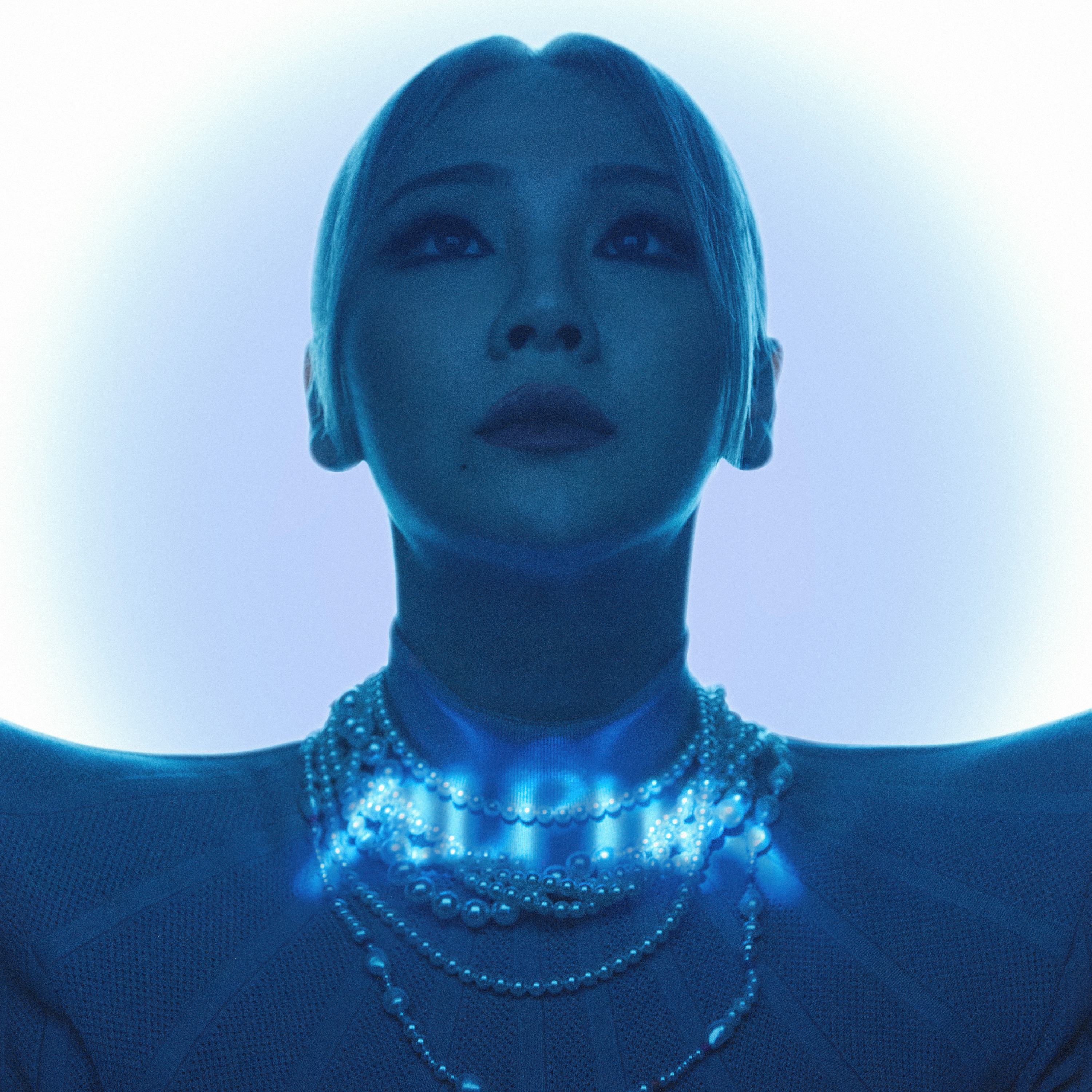 CL with a low ponytail, looking up, with a blue light shining over her 