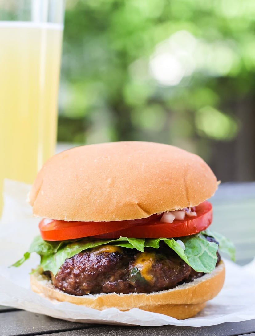 Jalapeno Bacon Cheddar burger on a plate with a glass of lemonade behind it