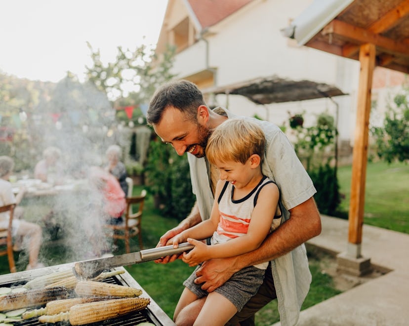 Father and young son, smiling, grilling together