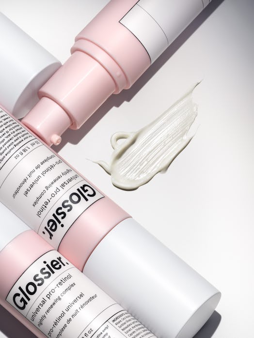 Three of Glossier's Universal Pro-Retinol creams and a swatch of the product in the brand's millenni...