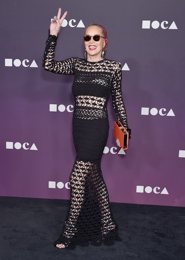 Sharon Stone wearing a floor length black knit gown with cutouts and red knit beanie at the MOCA Ben...