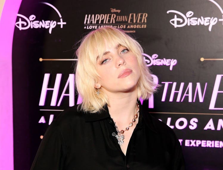Billie Eilish posing at the Premiere of her new concert film in a black shirt-dress