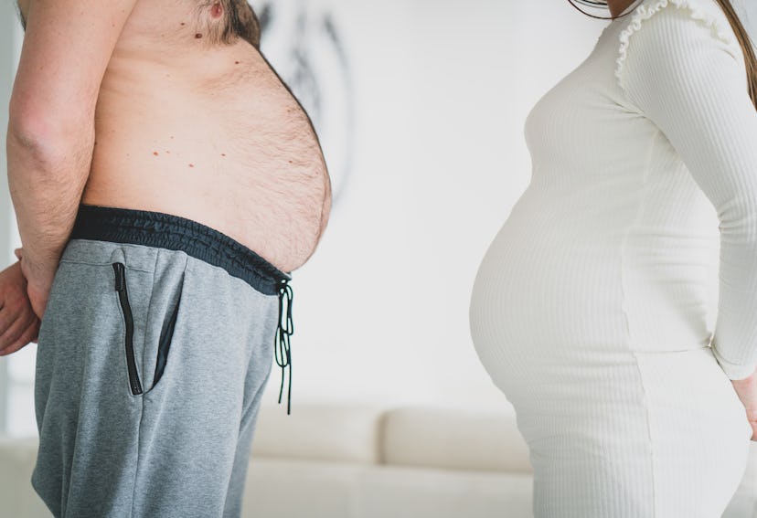 pregnant woman and man with rounded stomach standing belly to belly in an article about funny pregna...