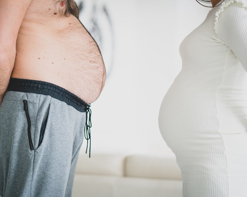 pregnant woman and man with rounded stomach standing belly to belly in an article about funny pregna...